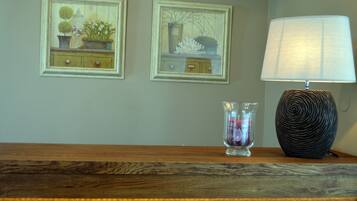 A wooden table with a lamp and two framed pictures on the wall.