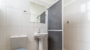 Et badeværelse med toilet, vask og brusekabine.