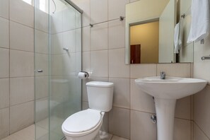 A bathroom with a glass shower enclosure, a toilet, and a sink. - Hotel L'espace - Jaragua Belo Horizonte (Belo Horizonte)