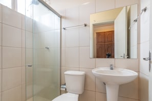 A bathroom with a glass shower enclosure, a white toilet, and a white sink. - Hotel L'espace - Jaragua Belo Horizonte (Belo Horizonte)