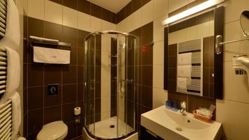 Ein modernes Badezimmer mit einer Glastrennwand-Dusche, einem weißen Waschbecken und einer Toilette.