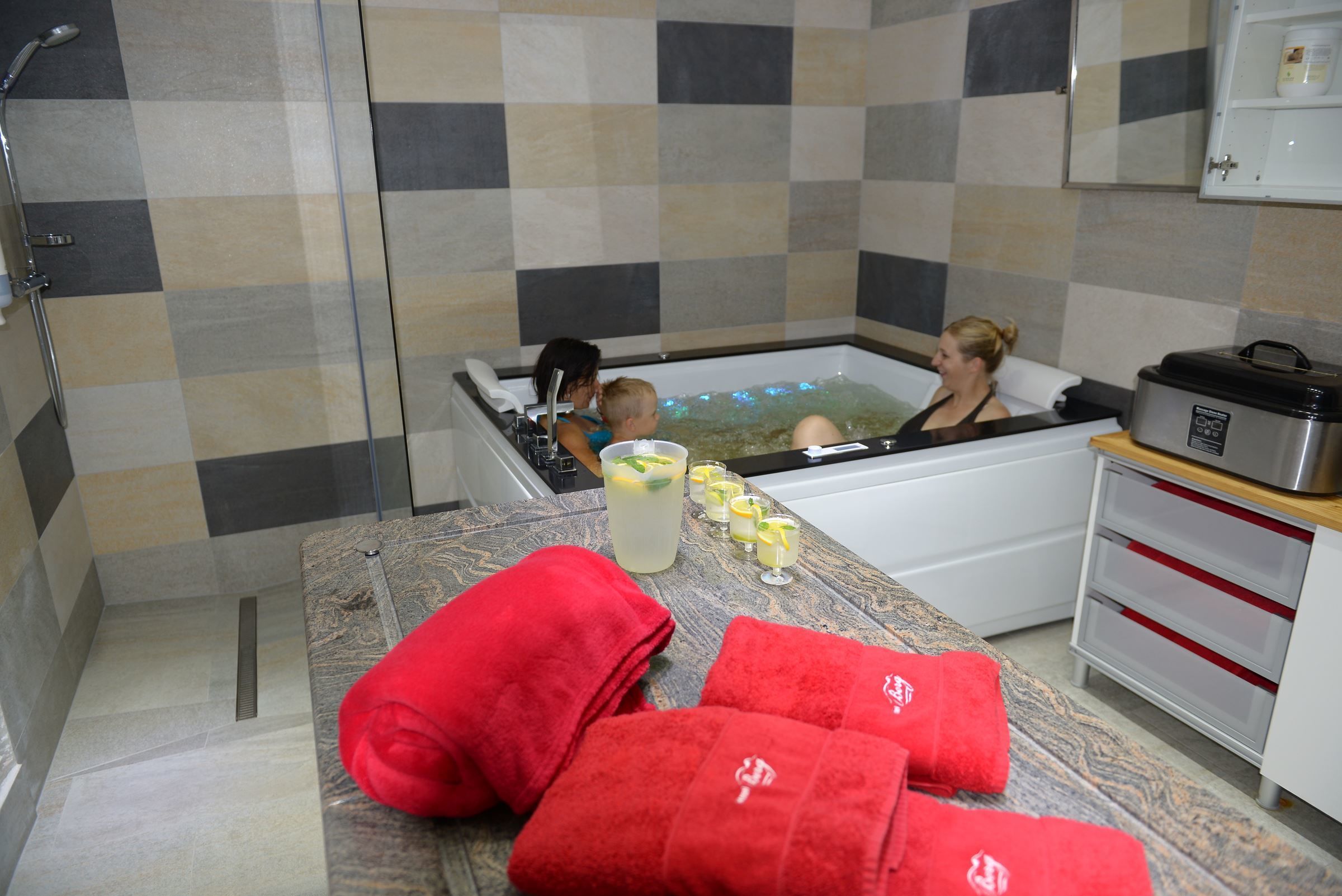 A bathroom with a bathtub, a shower, and a countertop with towels and glasses of water.