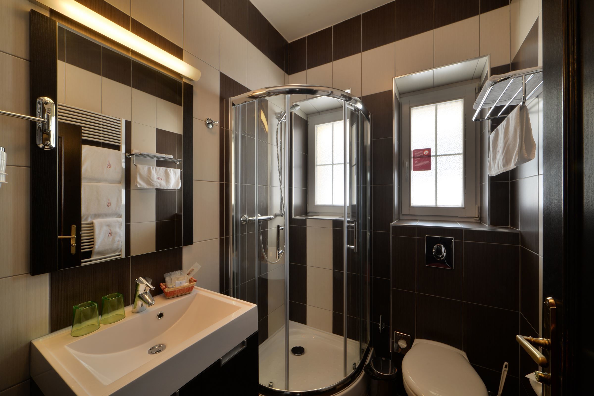 Ein modernes Badezimmer mit einer gläsernen Duschkabine, einem Waschbecken mit grünen Gläsern und einer Toilette.