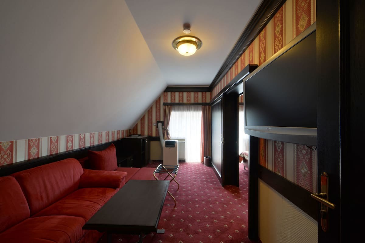 Ein Zimmer mit einem roten Sofa, einem kleinen Tisch, einem Heizkörper und einer Tür zu einem anderen Raum.