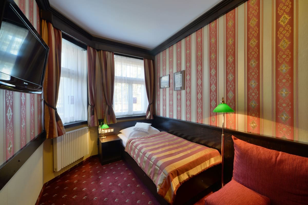 Ein Hotelzimmer mit Bett, Fernseher, Lampe und einem Fenster mit Vorhängen.