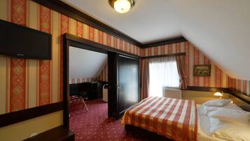 A hotel room with a bed, a desk, a chair, a wardrobe, and a television.