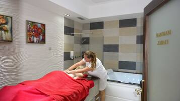 Een moderne spa-ruimte met een massagetafel, een douchegedeelte en een muur met een ruitpatroon.