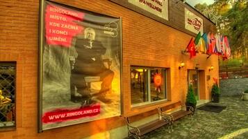 Un edificio con un grande cartellone pubblicitario per una spa e centro benessere. Sono presenti bandiere all'esterno ed è visibile una panchina di fronte all'edificio.