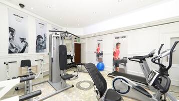 Un gimnasio con varios equipos de ejercicio, incluyendo una prensa de banca, una cinta de correr y una bicicleta estática.