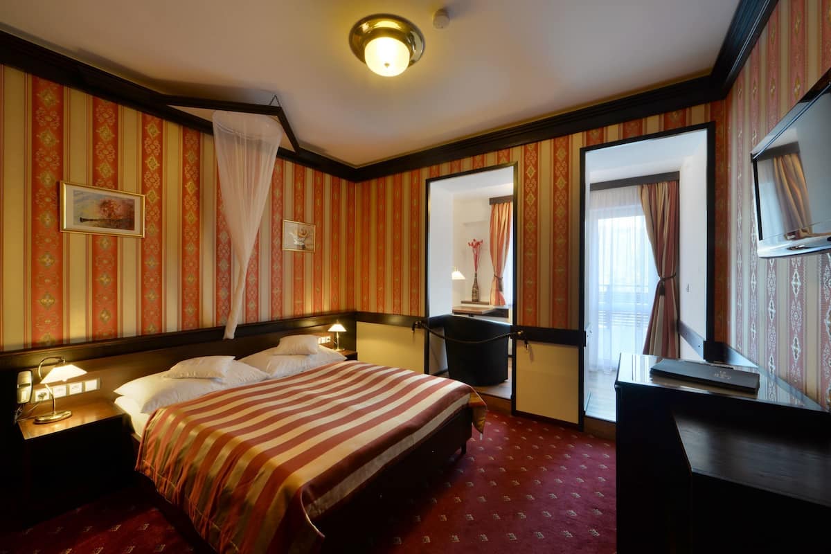 Ein Hotelzimmer mit Bett, Nachttischen, einem Schreibtisch und einem Spiegel.