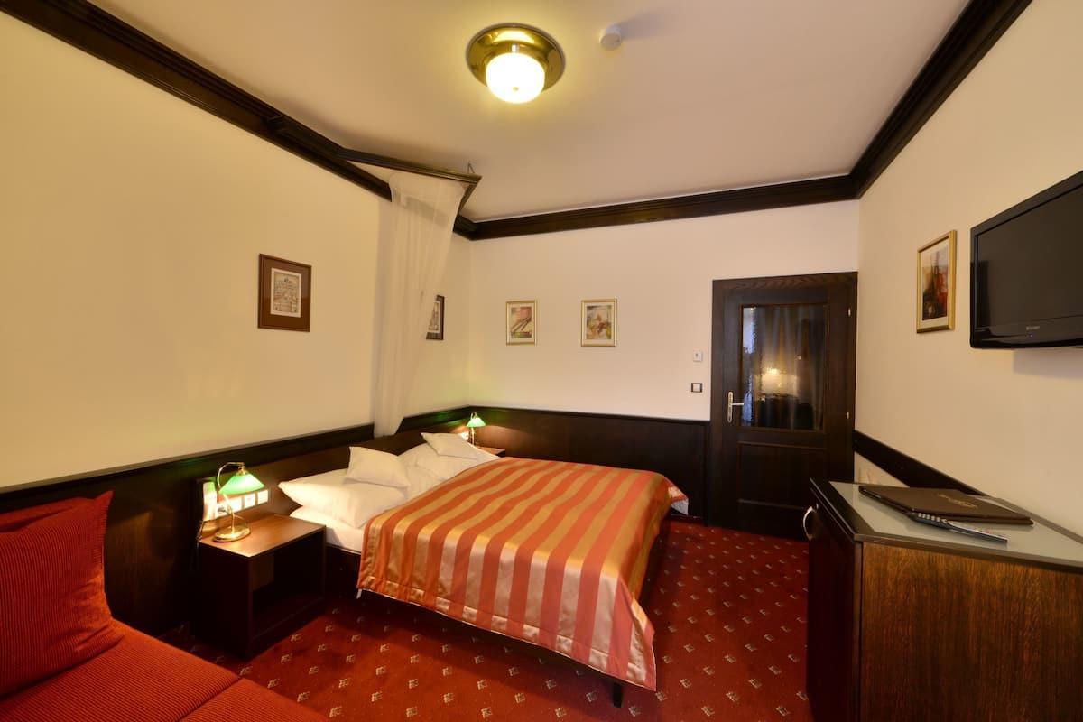 Ein Hotelzimmer mit Bett, Schreibtisch, Fernseher und Tür.