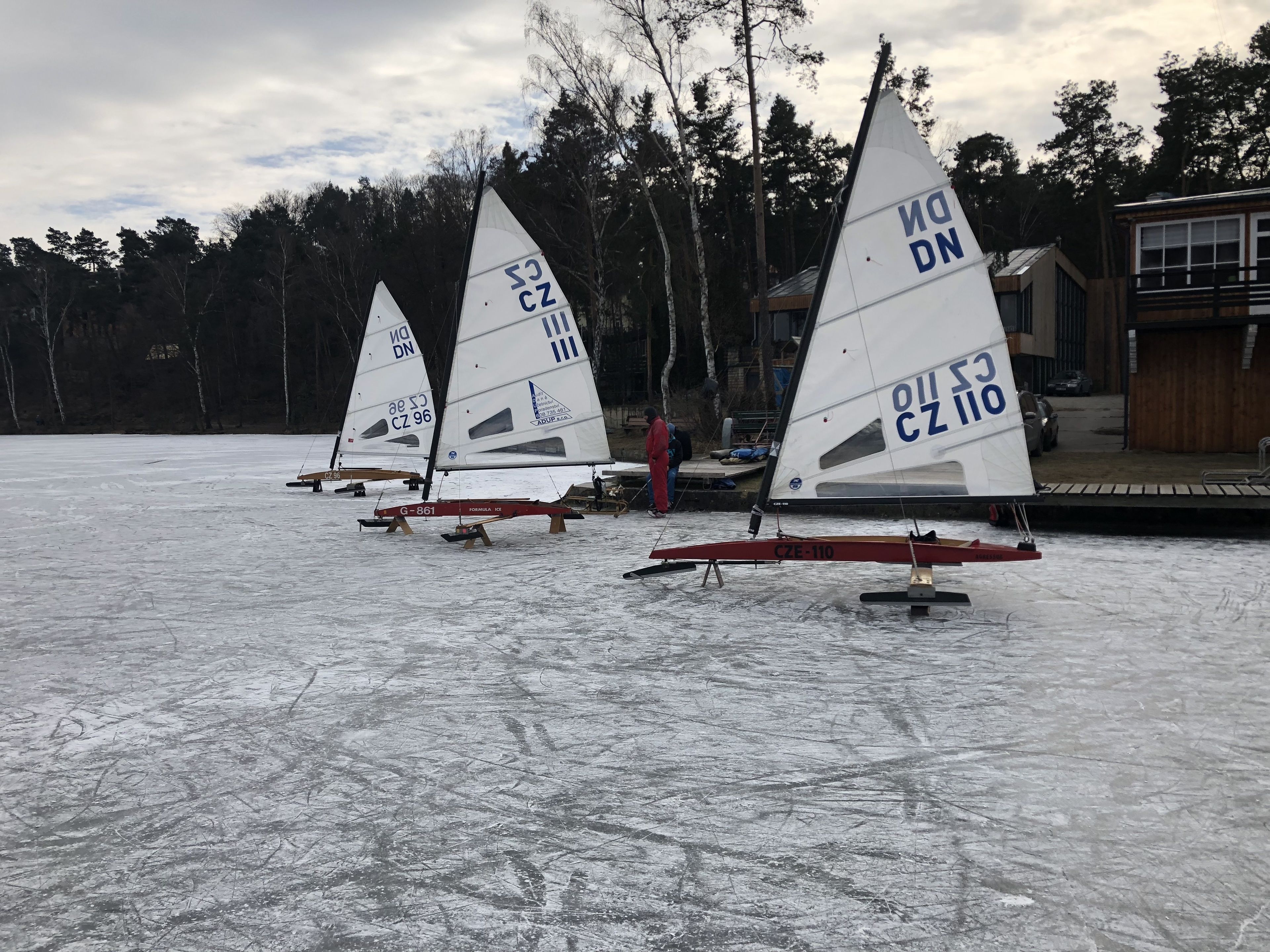 Sailboats on a frozen lake with a building in the background.