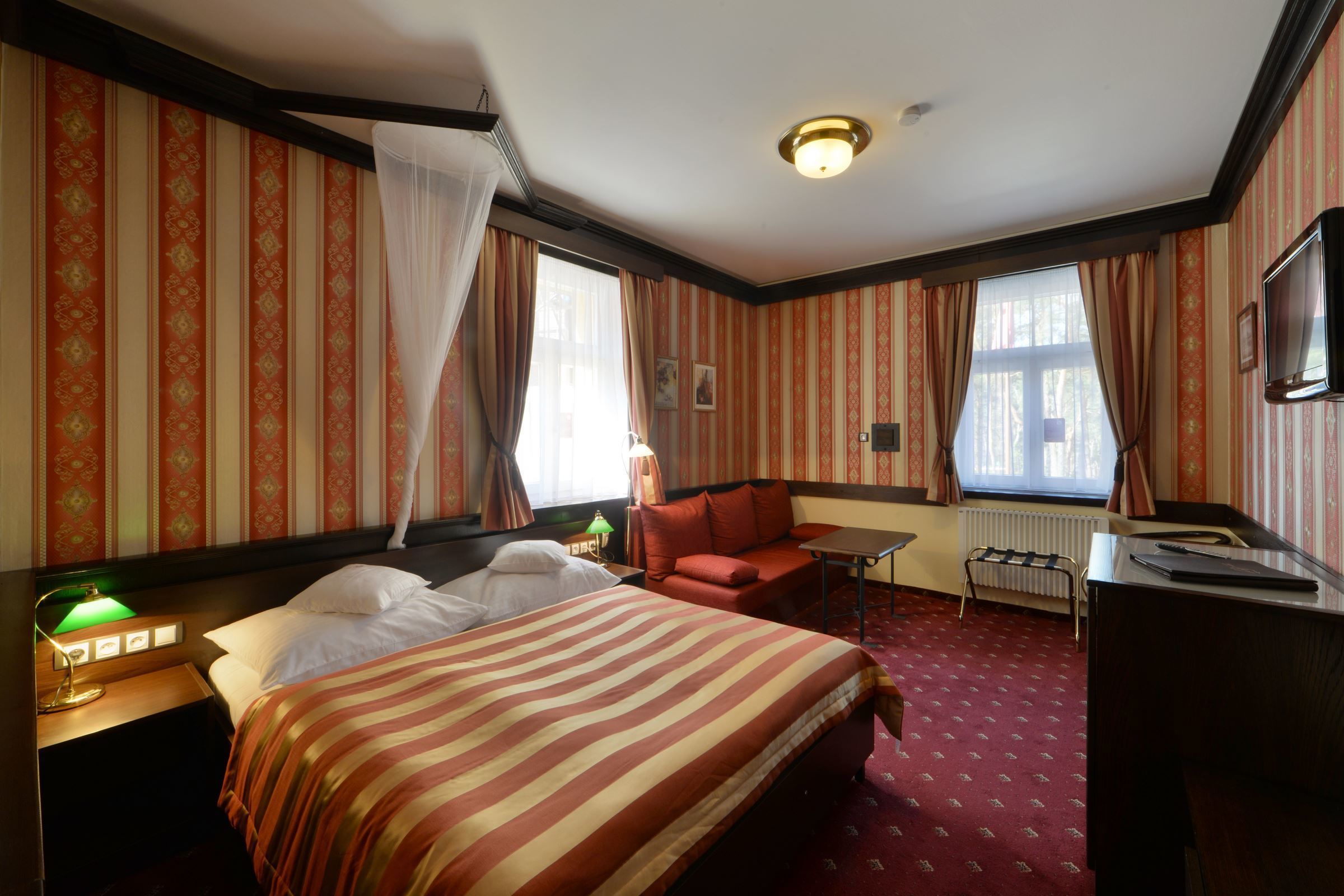 A hotel room with a bed, a desk, a chair, and a TV.