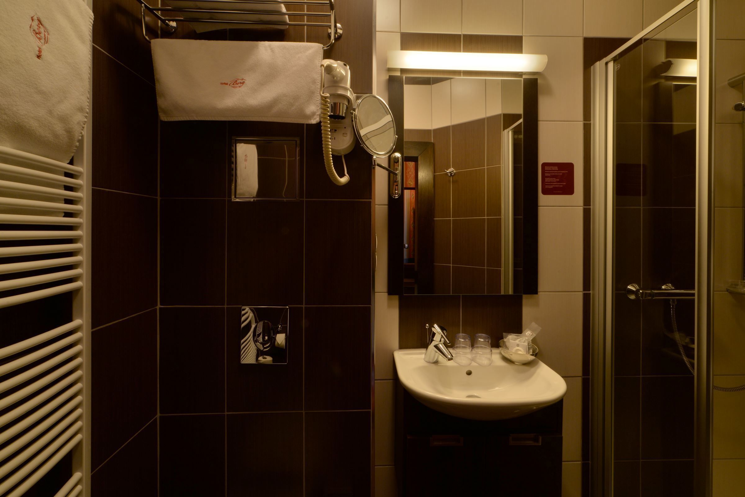 Une salle de bain équipée d’un lavabo, d’un miroir, d’un porte-serviettes et d’un espace douche.
