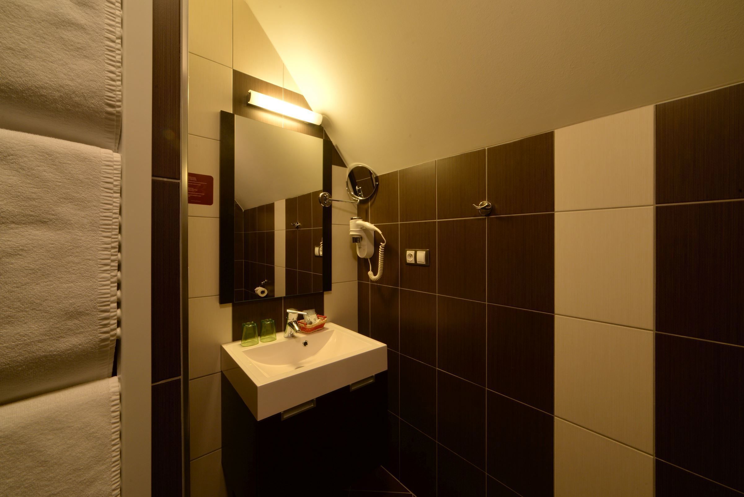 A modern bathroom with a white sink, a mirror, and a towel rack.