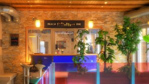 Un espace bar avec un mur en pierre, un plafond en bois et des plantes d’intérieur.