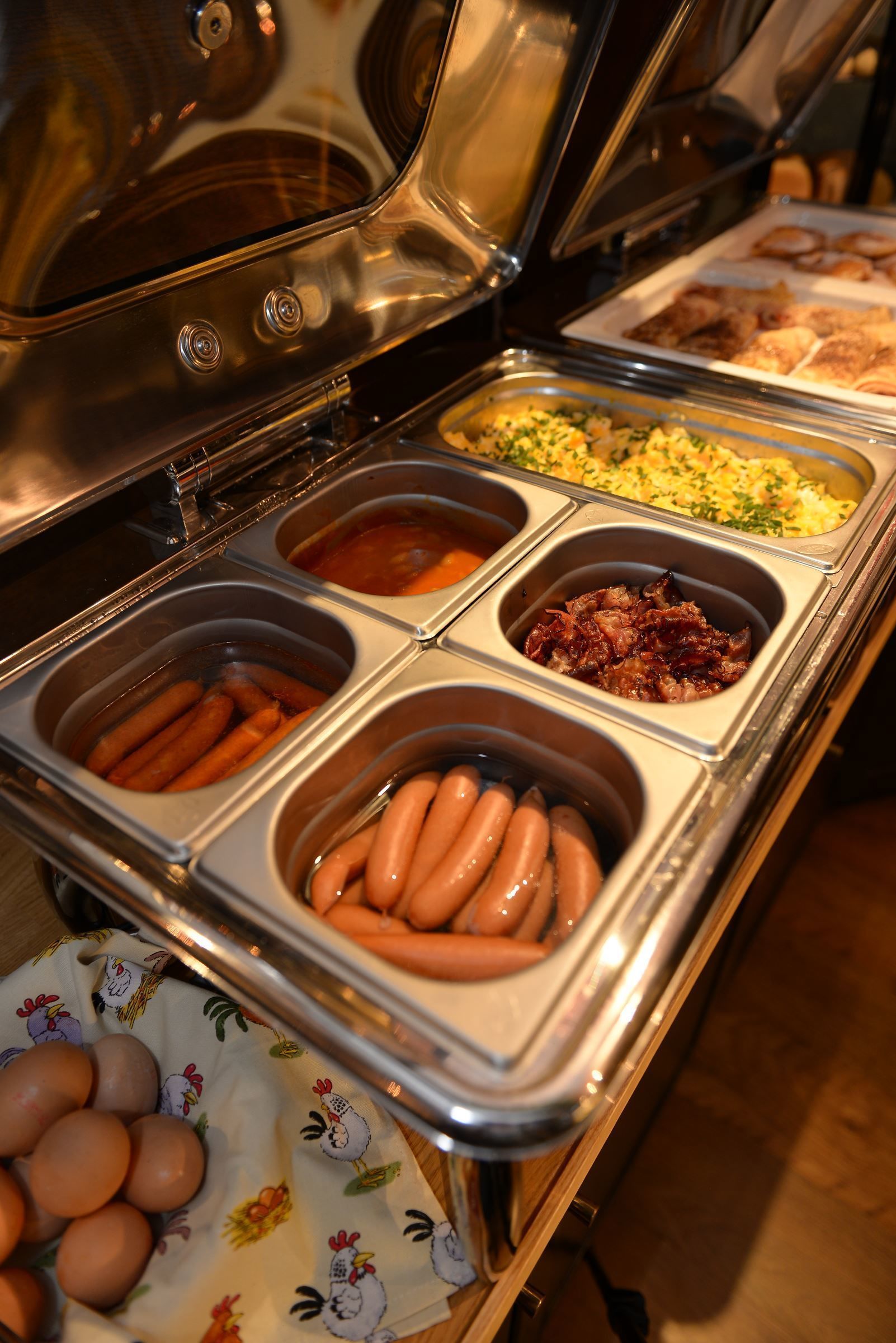 A buffet with various food items including sausages, eggs, and other dishes.