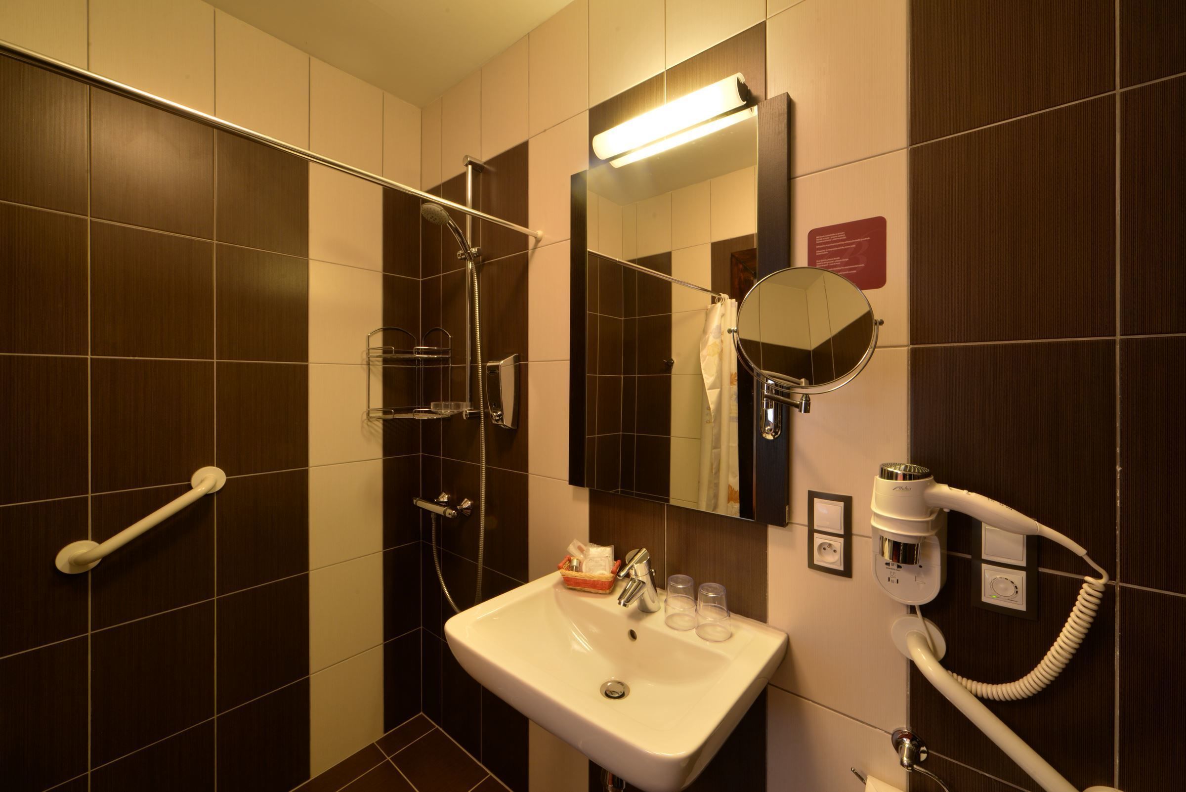 A bathroom with a shower, a sink, a mirror, and a hairdryer.