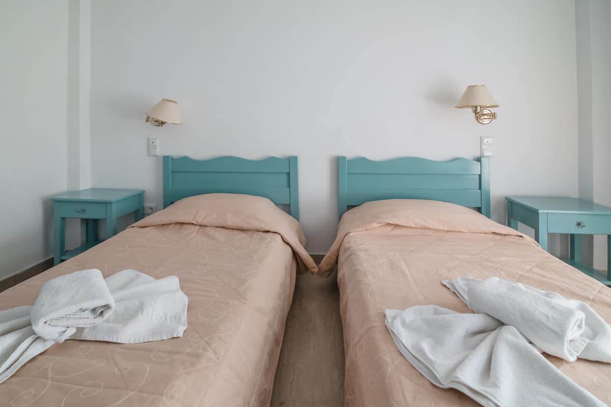 A twin room with two beds, each with a headboard, bedside tables, and lamps.