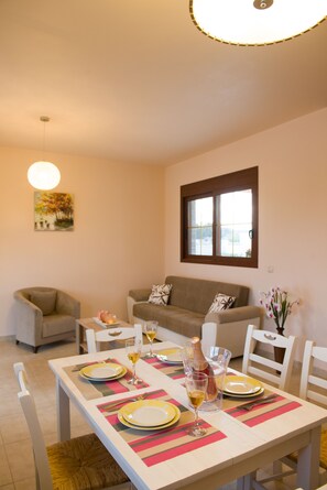 A dining area with a table set for four, a sofa, and a window with blinds.