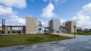 A modern building with a covered patio area, a pool, and a well-maintained lawn. - Petra Villas (Rhodes)