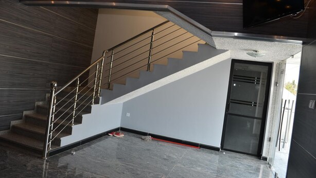 A modern interior with a staircase, a flat-screen TV mounted on the wall, and a door leading to another room. - Hotel Pacific (Nacala)