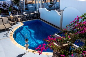 Una piscina con un muro de piedra y un edificio blanco al fondo.