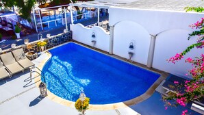 Una piscina amb un solàrium blanc, envoltada de gandules i plantes en testos.