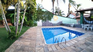Una piscina con baldosas de piedra, rodeada de vegetación y un mural.