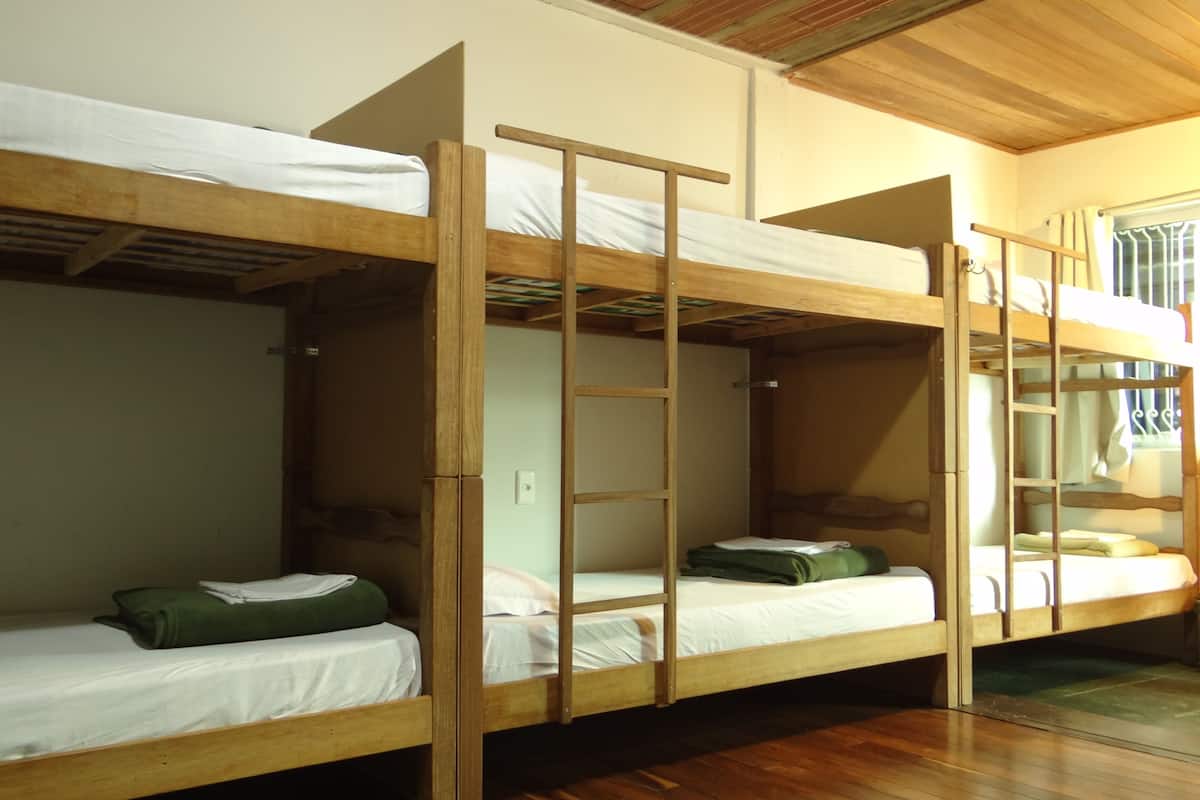 Quarto com beliches de madeira e roupa de cama branca.