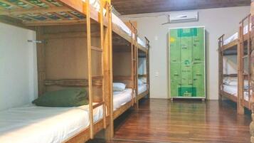 Un dormitorio con literas, suelo de madera y zona con taquillas verdes.