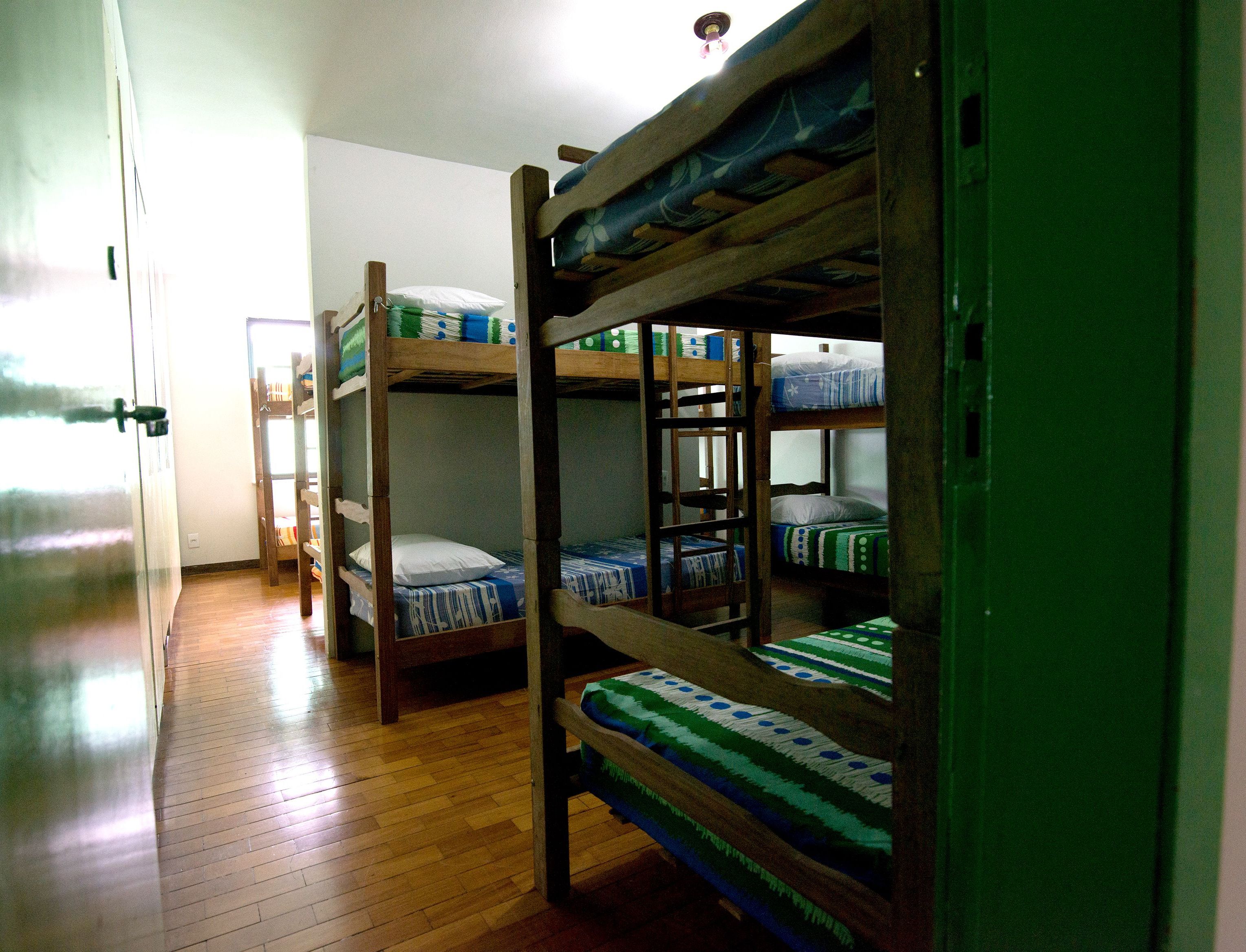 Una habitación con literas, suelo de madera y una puerta que da a otra habitación.