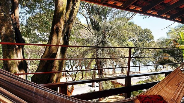 Una hamaca bajo una estructura de madera con vistas a árboles y una carretera.