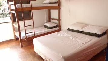 Quarto com beliche, uma escada de madeira, uma cama de solteiro e uma prateleira sobre a cama.