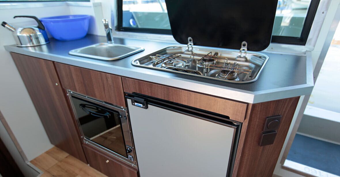 A compact kitchenette with a built-in oven, a sink, and a stove.
