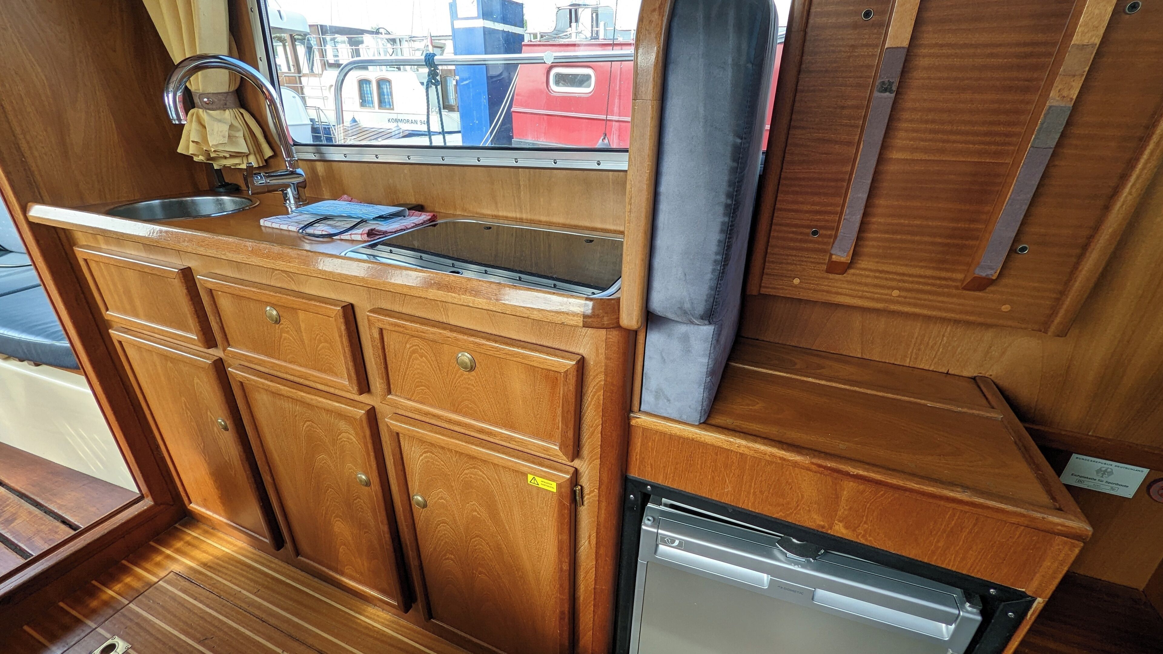 A compact kitchenette with wooden cabinets, a sink, and a dishwasher.
