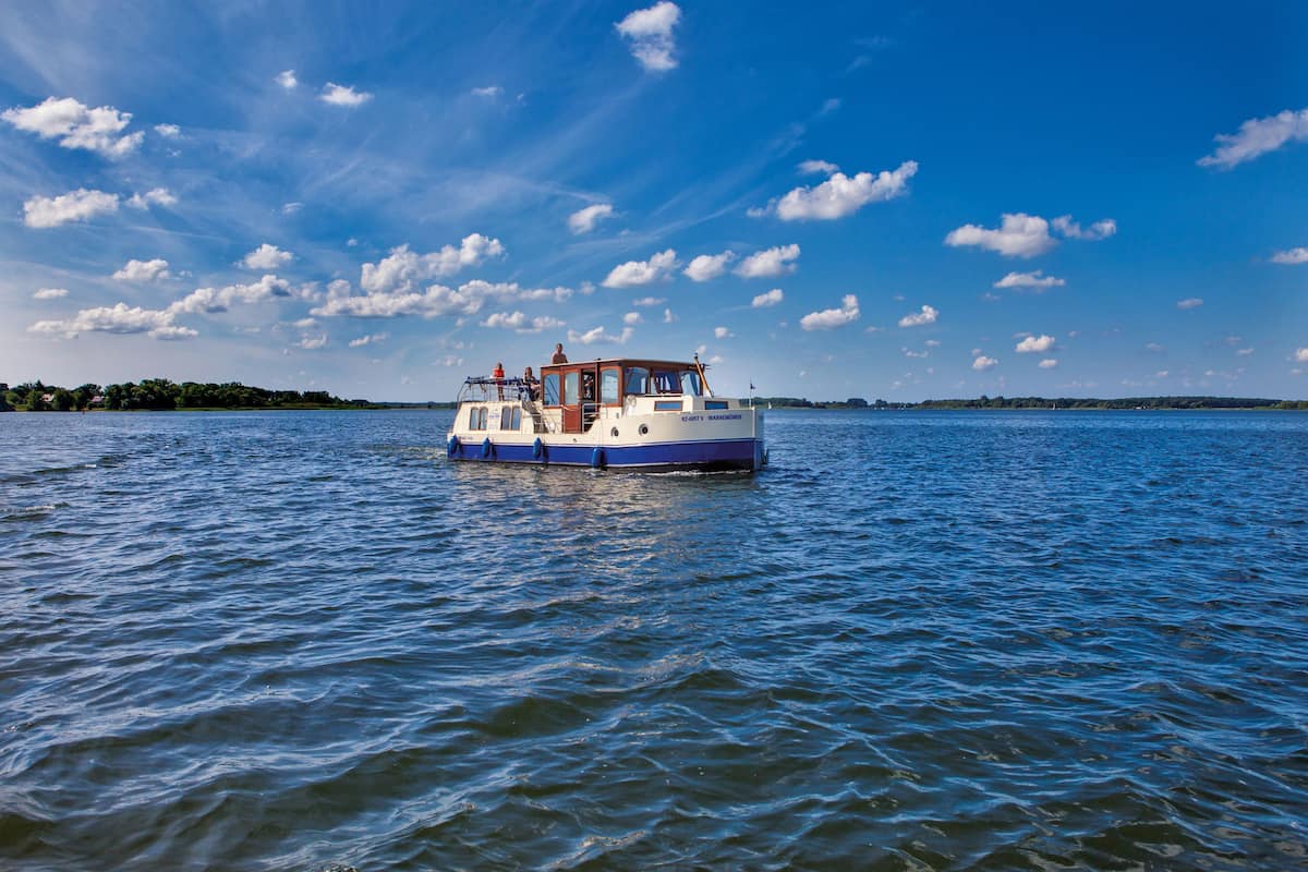A boat with a cabin and open deck, floating on calm water.