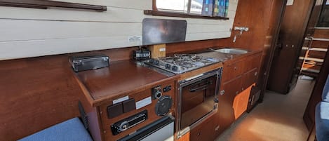 Cocina compacta con estufa a gas, horno y lavaplatos.