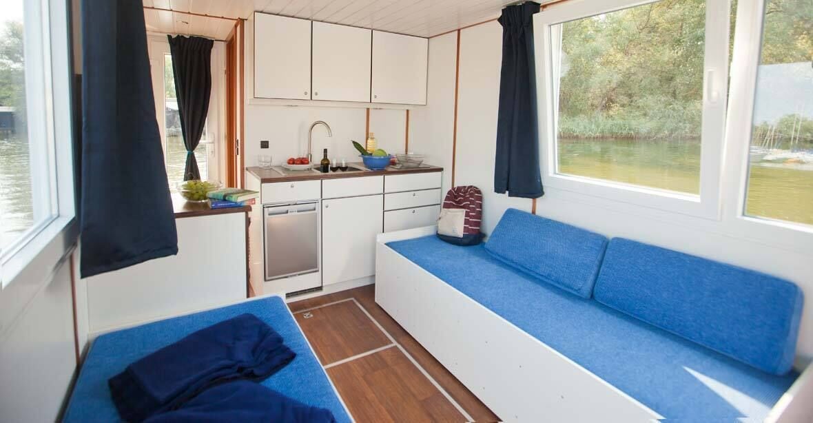 Una cabaña acogedora con kitchenette, un sofá azul y una mesita.