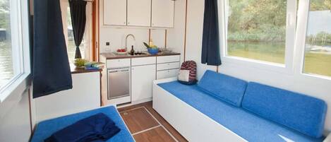 A compact cabin with a kitchenette, a blue sofa, and a small table.