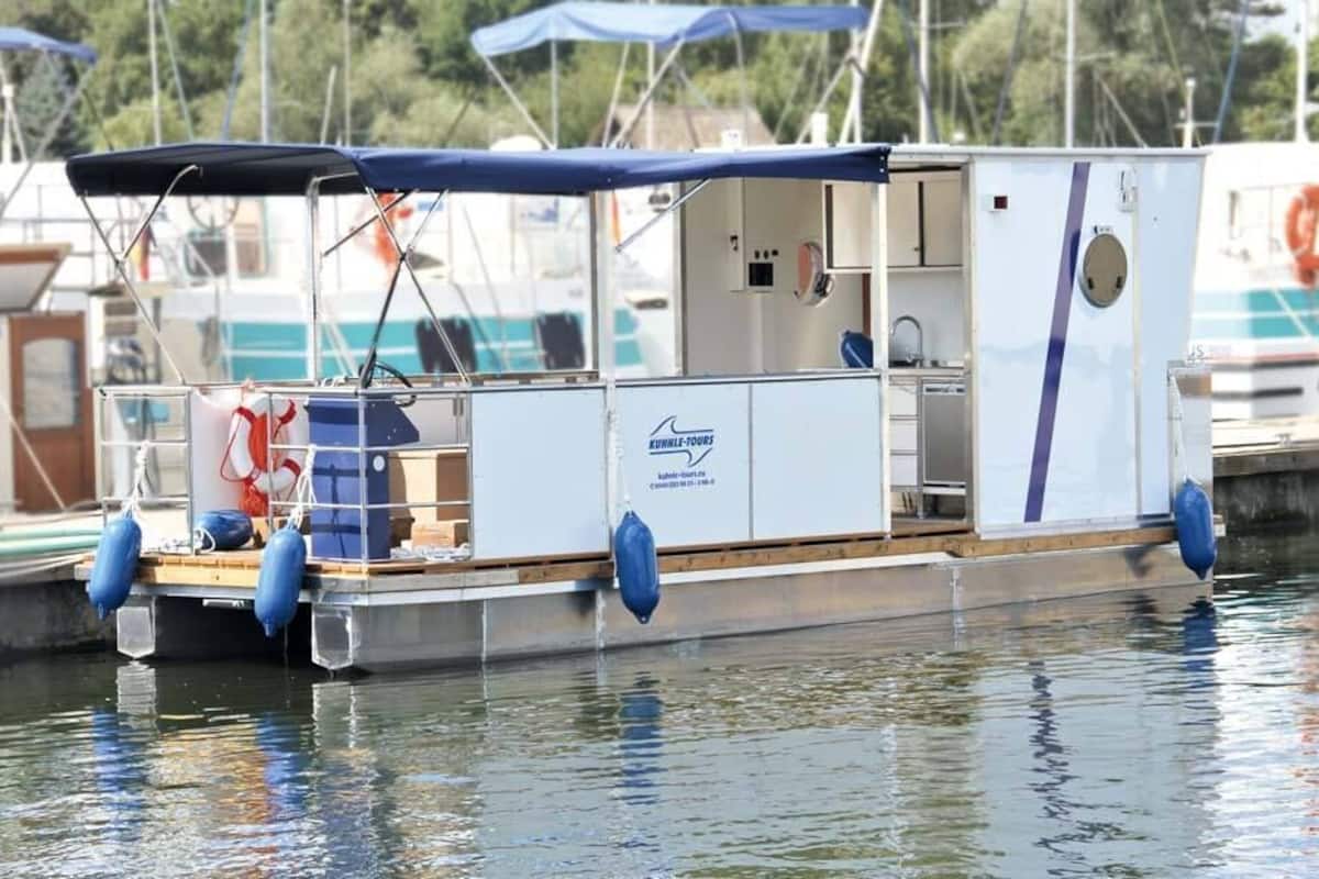 A small, enclosed boat with a covered seating area, a small kitchen, and a bathroom.