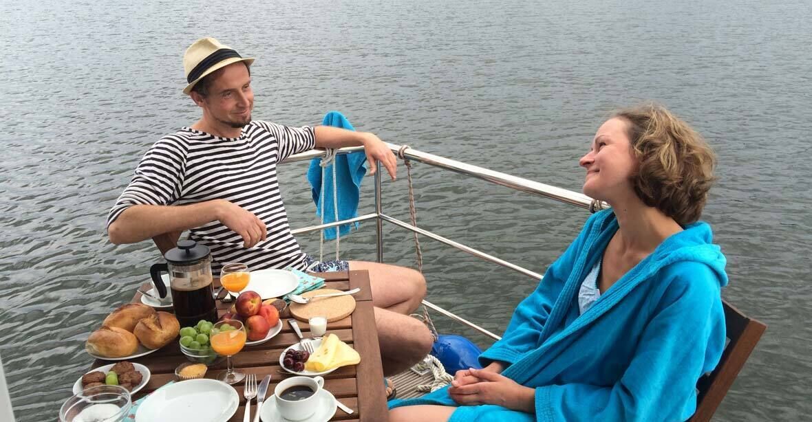 Pariskunta veneessä, ja pöytä on katettu aamiaista varten.
