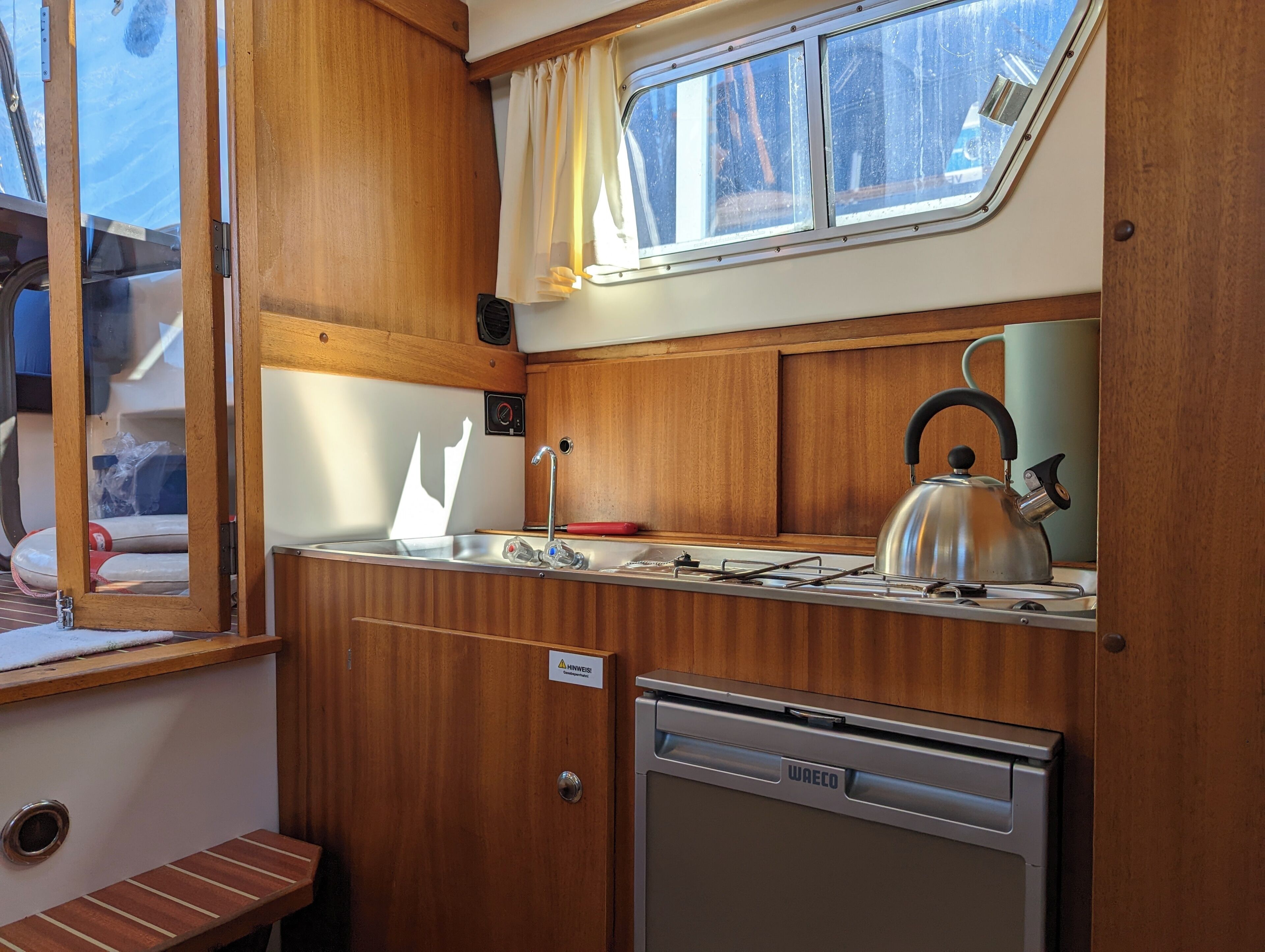 A compact kitchenette with a sink, stove, and kettle.
