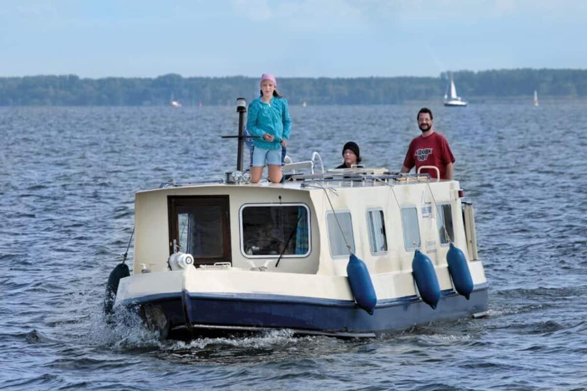 A small boat with two people on board, moving on a body of water.