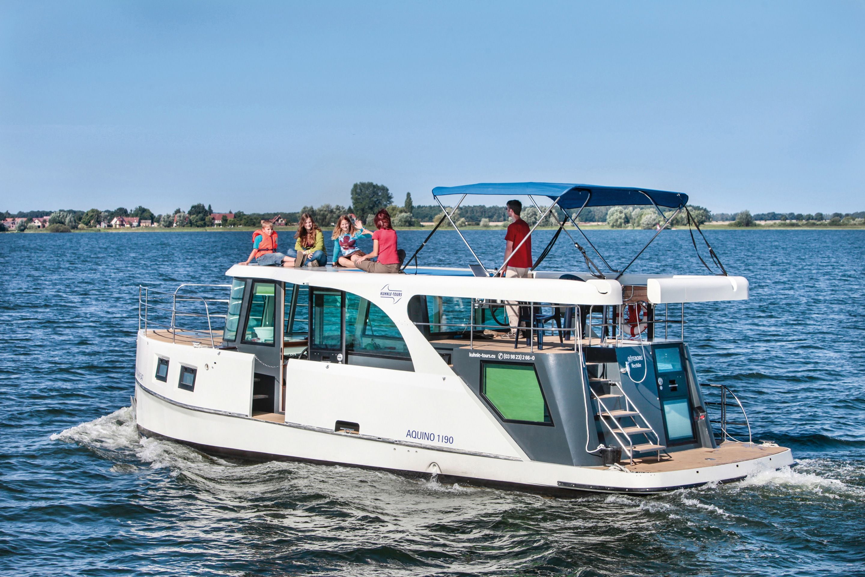 Ein mittelgroßes Boot mit überdachter Aufbaustruktur, einer Kabine und einer Bugwelle.