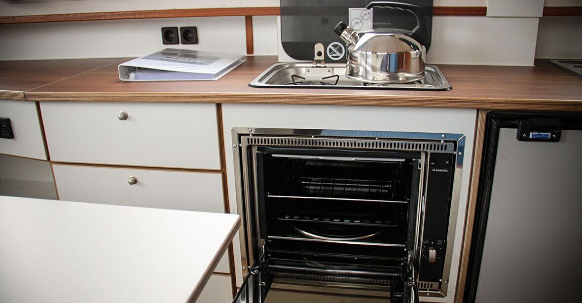 A compact kitchenette with a built-in oven, a coffee maker, and a small sink.