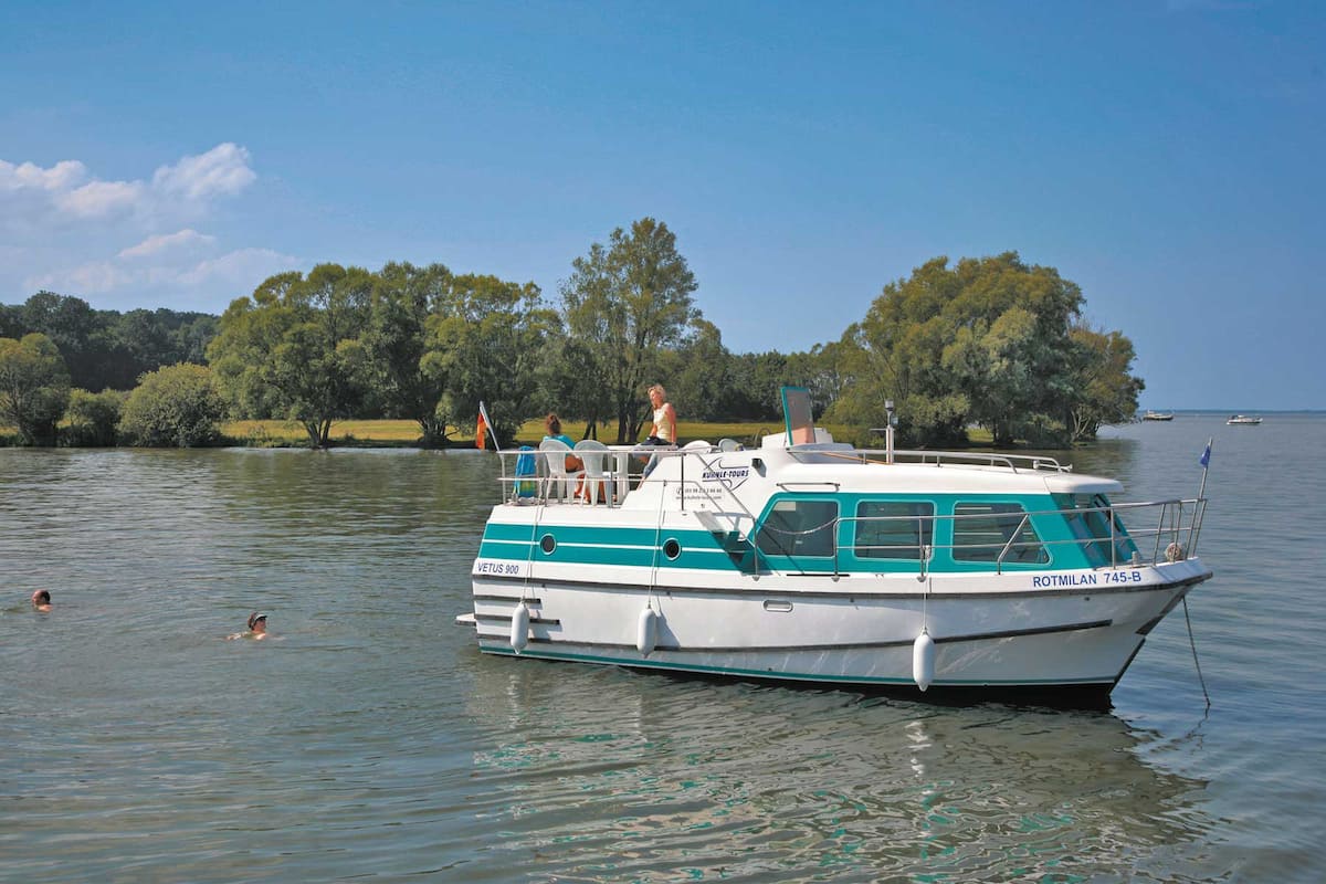 A boat with a cabin and a deck, floating on calm water.