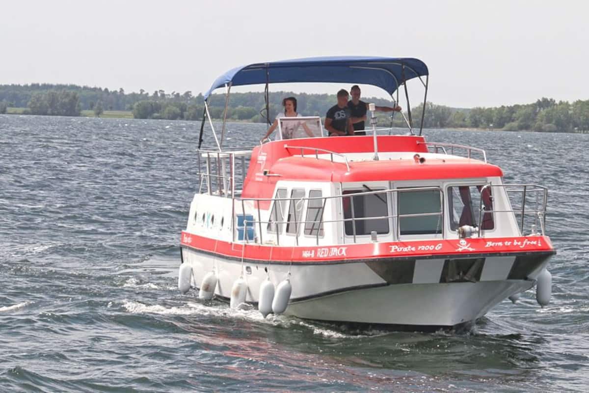 A small motorboat with a red and white color scheme, a canopy, and a few passengers.