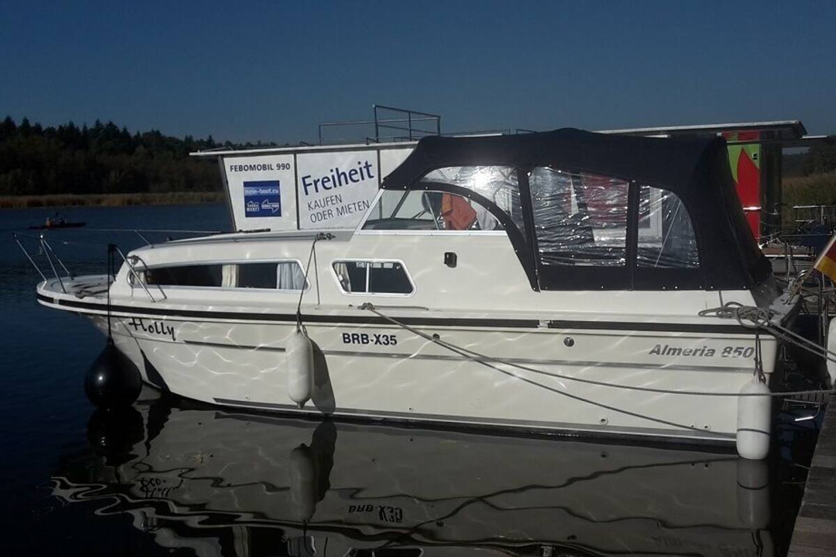 A boat named 'Holly' docked at a marina with a sign indicating 'Freiheit' and 'Almeria 850'.