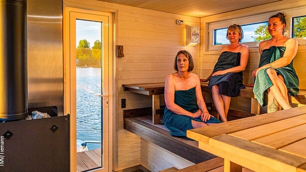 Un sauna con bancos de madera y un ventanal grande con vista a un cuerpo de agua.